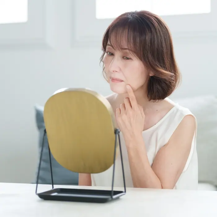 鏡を見て悩んでいる女性
