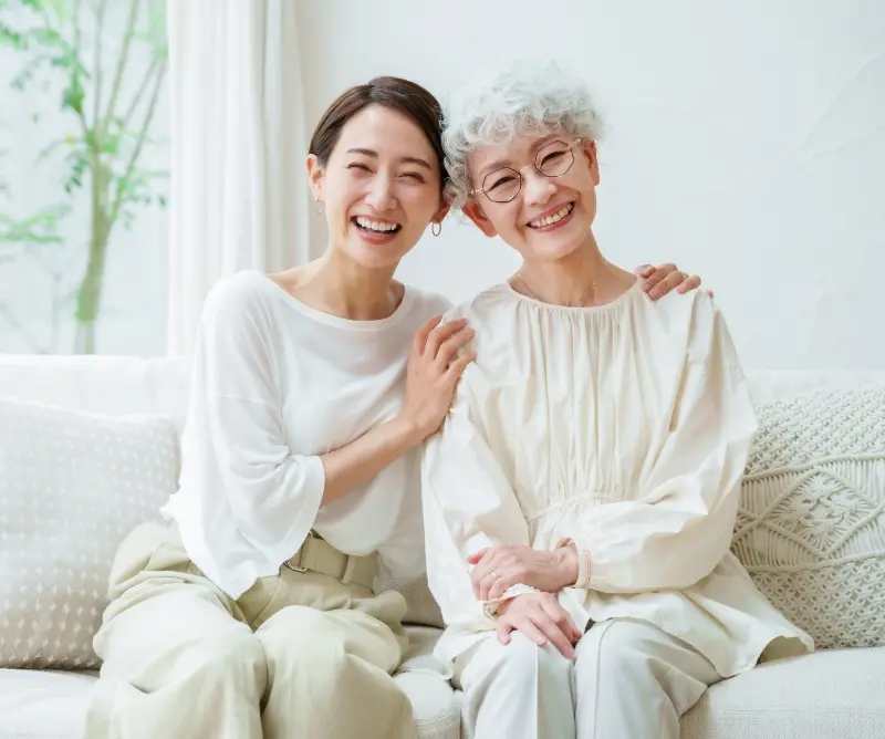 笑顔のご高齢の女性と、笑顔でご高齢の女性の肩に手を添えている女性